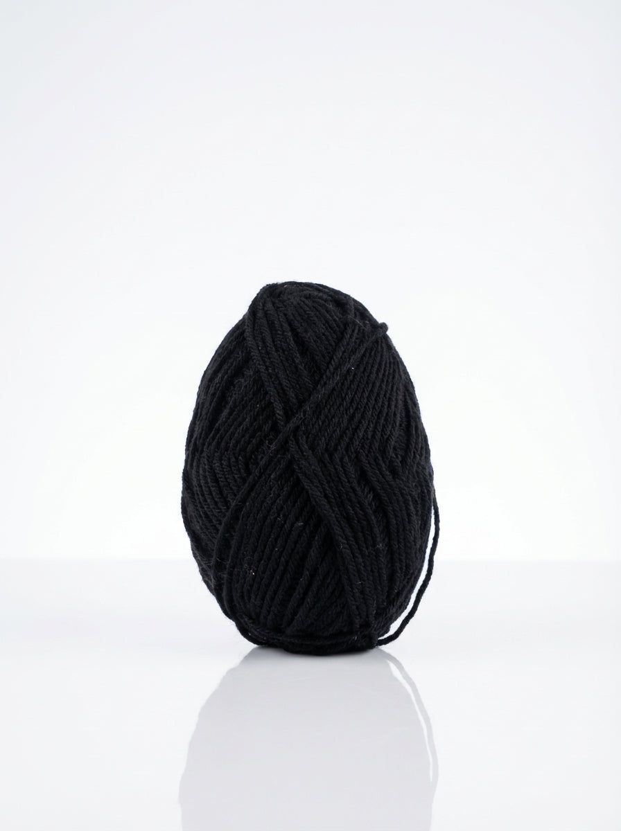 Studio shot of a 50g skein of black milk cotton yarn, showcasing its soft texture and matte finish.