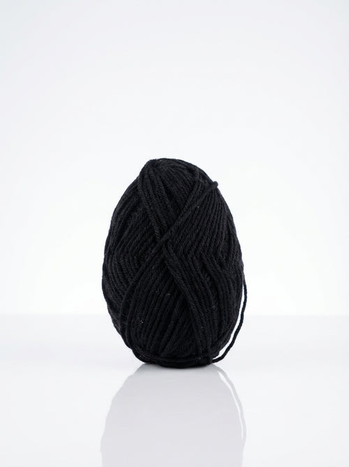Studio shot of a 50g skein of black milk cotton yarn, showcasing its soft texture and matte finish.