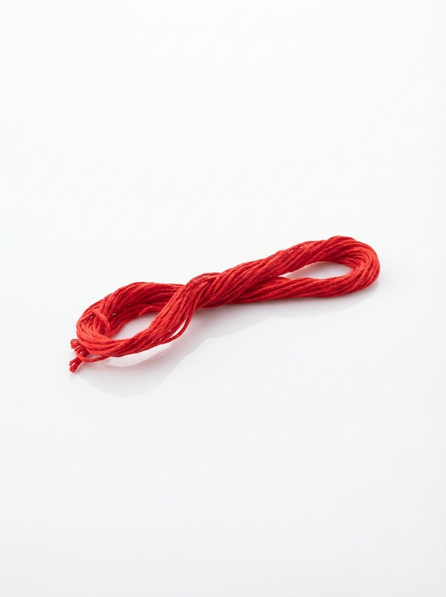 Skein of light Christmas red cotton embroidery floss, close-up showing soft texture and vibrant color.