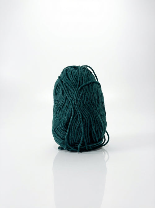 Studio shot of peacock green cotton yarn ball, showcasing its texture and vibrant color, suitable for crafting.