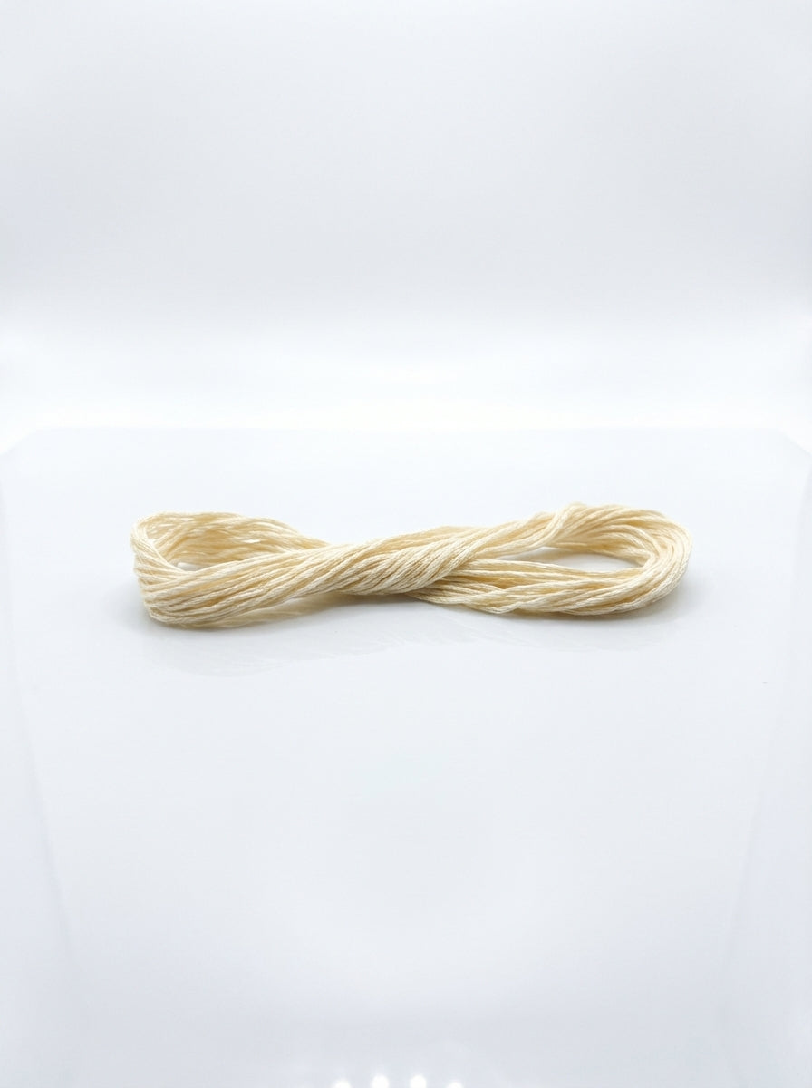 Close-up of a cream cotton embroidery floss skein showing texture and smooth matte finish.