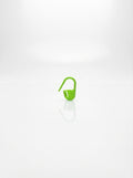Close-up studio shot of a green plastic crochet latch clip hook for marking stitches.
