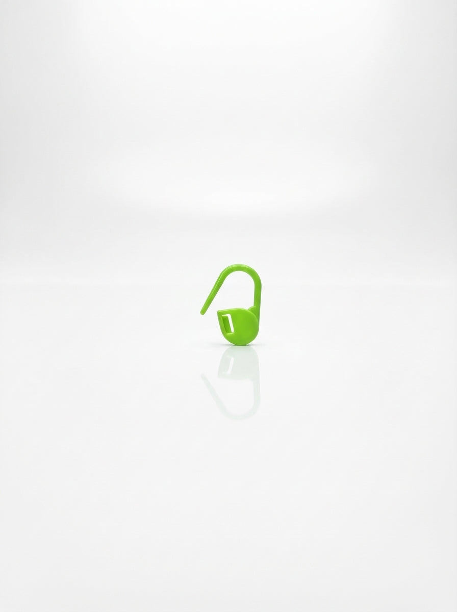 Close-up studio shot of a green plastic crochet latch clip hook for marking stitches.