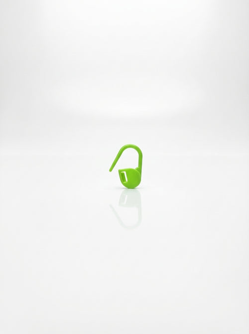 Close-up studio shot of a green plastic crochet latch clip hook for marking stitches.