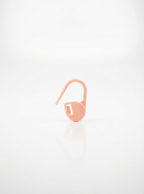 Light pink crochet latch clip hook for marking stitches, smooth plastic finish, close-up studio shot.