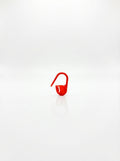 Studio shot of a red plastic crochet latch clip hook, a small tool used for marking stitches. Focus on shape and color.