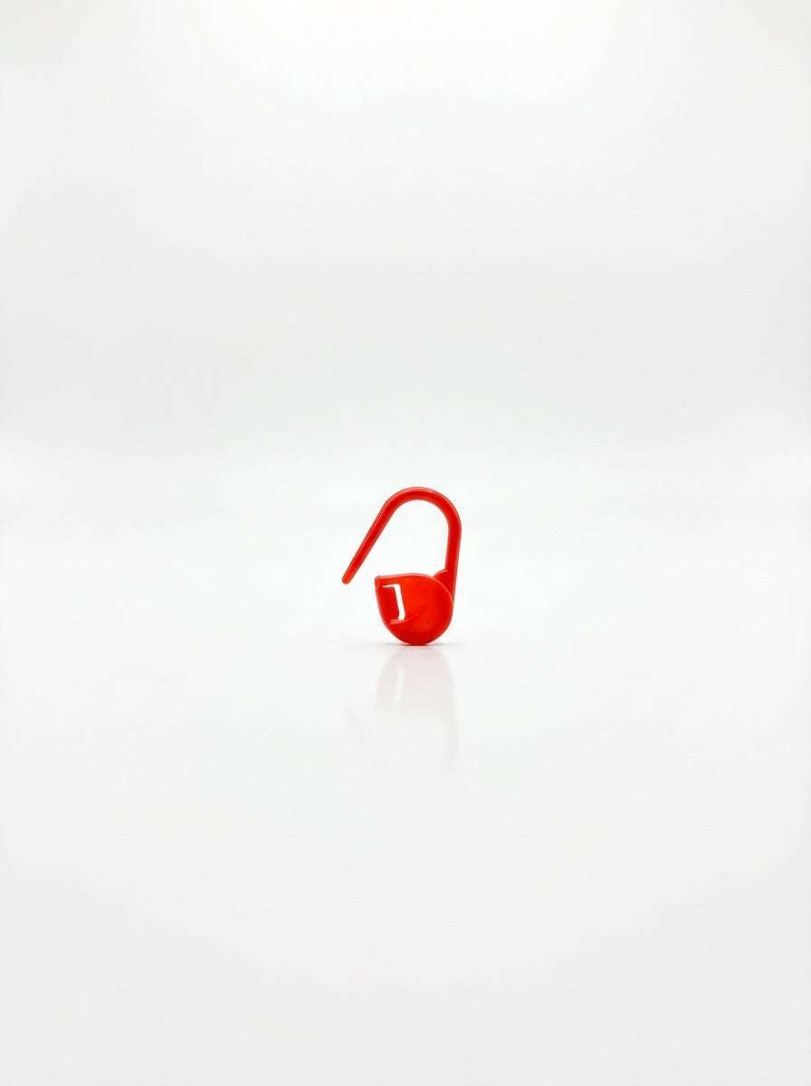 Studio shot of a red plastic crochet latch clip hook, a small tool used for marking stitches. Focus on shape and color.