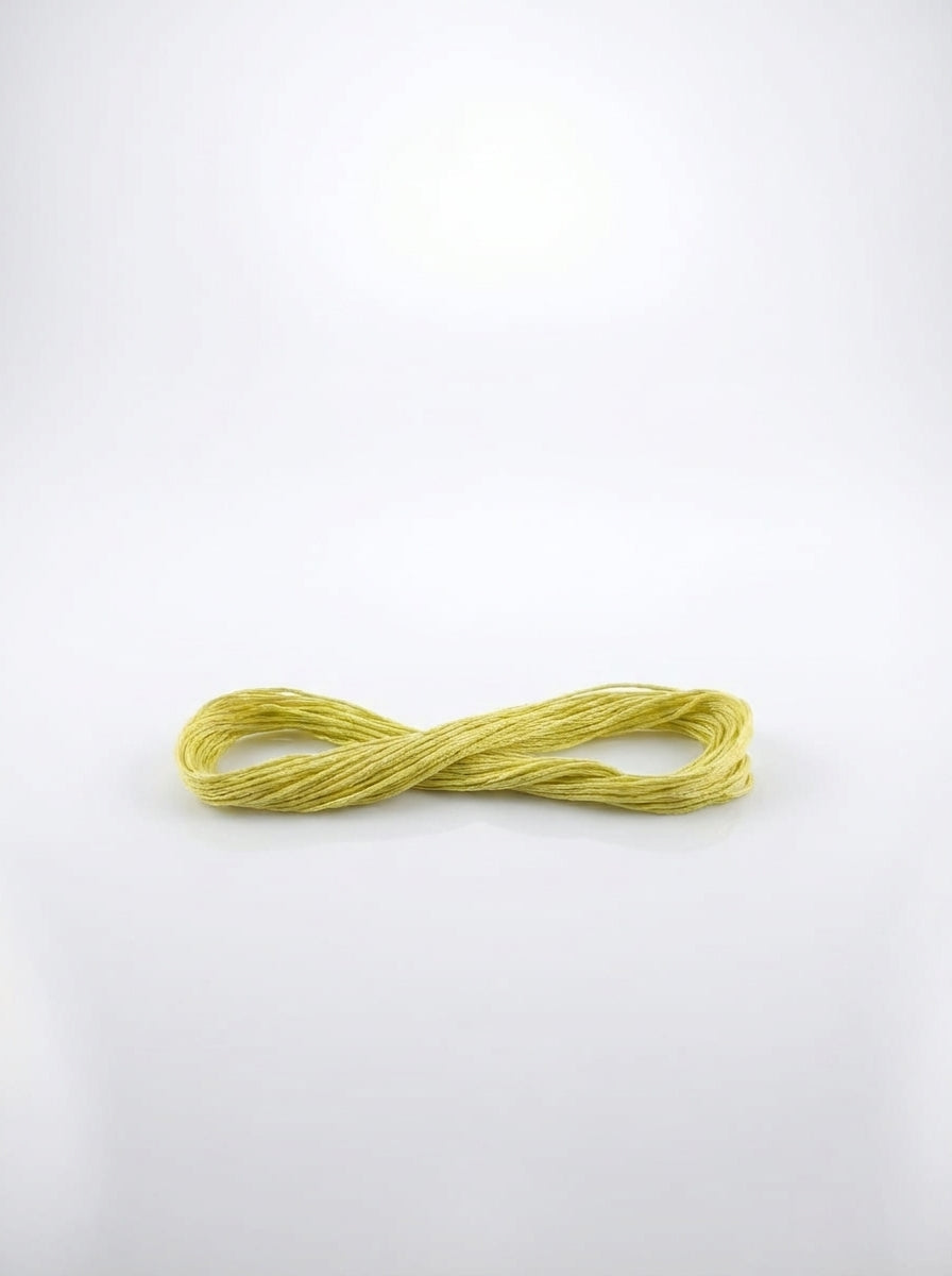 Skein of light avocado green embroidery floss made of soft cotton threads, close-up studio shot showing texture and color.