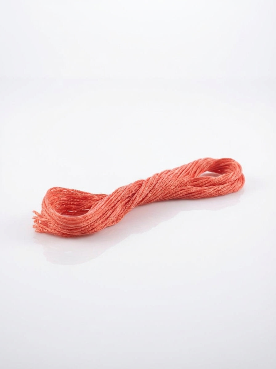 Close-up of a coral embroidery thread skein, showing the soft cotton texture and vibrant color.